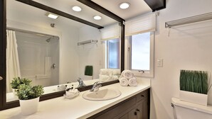 Un bagno con un lavandino bianco, uno specchio grande, un porta asciugamani e un water.
