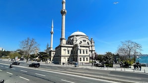 Un grand bâtiment doté d’un dôme imposant et de deux hauts minarets, situé au bord de l’eau.