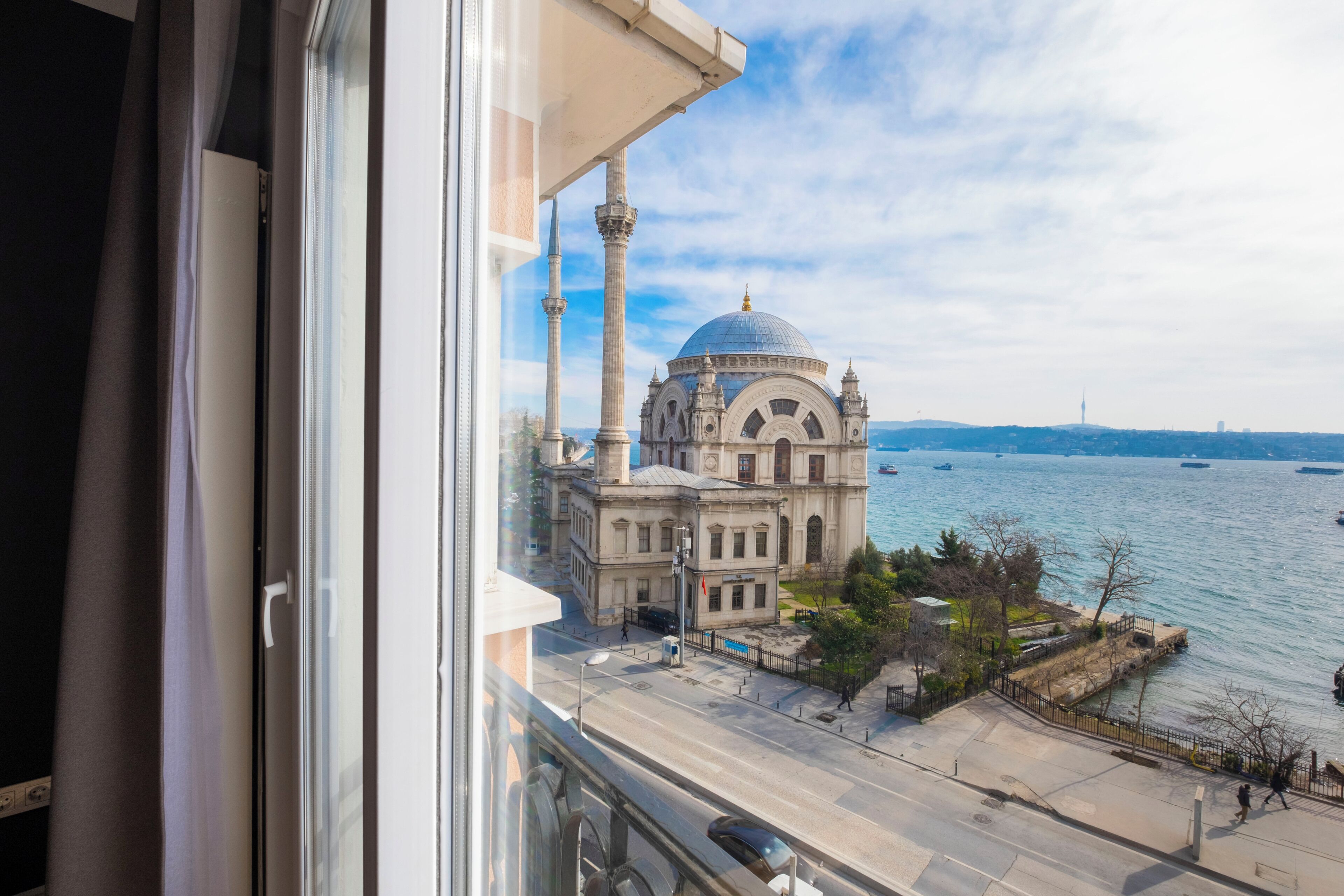 A view of a historic building with a dome and minarets, overlooking a waterfront with a clear sky.