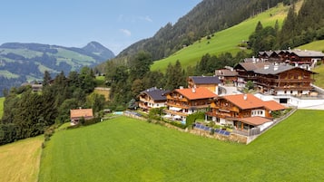 Un chalet situé sur une colline, composé de plusieurs bâtiments en bois, doté d’une piscine et de panneaux solaires.
