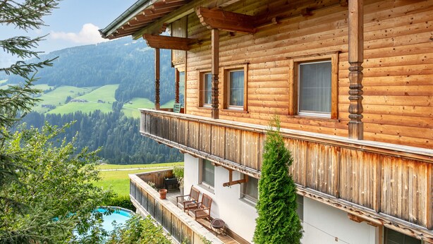 Eine Holzhütte mit Balkon mit Blick auf eine Berglandschaft.