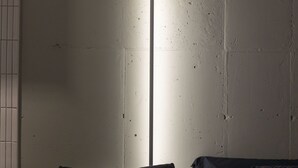 Ein Zimmer mit einem Bett, einem Nachttisch und einer Wand-Klimaanlage.