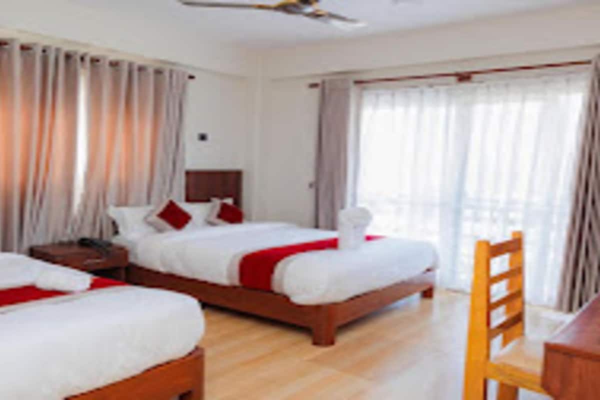 A hotel room with two beds, a wooden table, and a chair.
