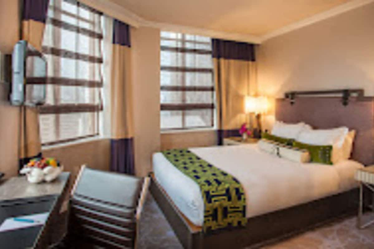A hotel room with a bed, bedside tables, a desk, and a chair.