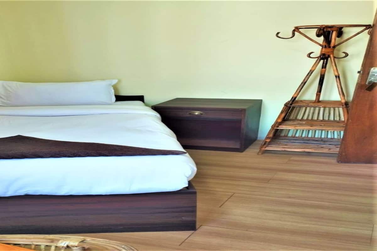 A bed with a dark wooden frame, white bedding, and a red curtain.