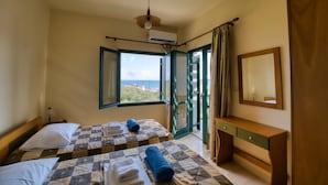 A hotel room with two beds, a bedside table, a mirror, and a view of the sea. - erodios apartments (Apokoronas)