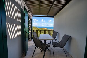 A balcony with a table and chairs, overlooking a scenic view of the sea and hills. - erodios apartments (Apokoronas)