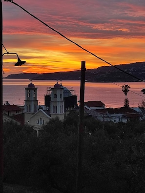 A coastal sunset with two church towers silhouetted against the sky.