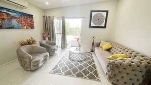 A living room with a sofa, armchair, and a round coffee table. There is a painting on the wall and a decorative piece above the sofa. - Beautiful modern family home ,centrally located ,close to everything (Bli Bli)