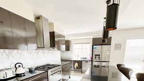 A modern kitchen with stainless steel appliances, a large island, and a hanging light fixture. - Beautiful modern family home ,centrally located ,close to everything (Bli Bli)