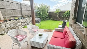 A covered patio with wicker furniture, a stone wall, and a view of the backyard. - Beautiful modern family home ,centrally located ,close to everything (Bli Bli)