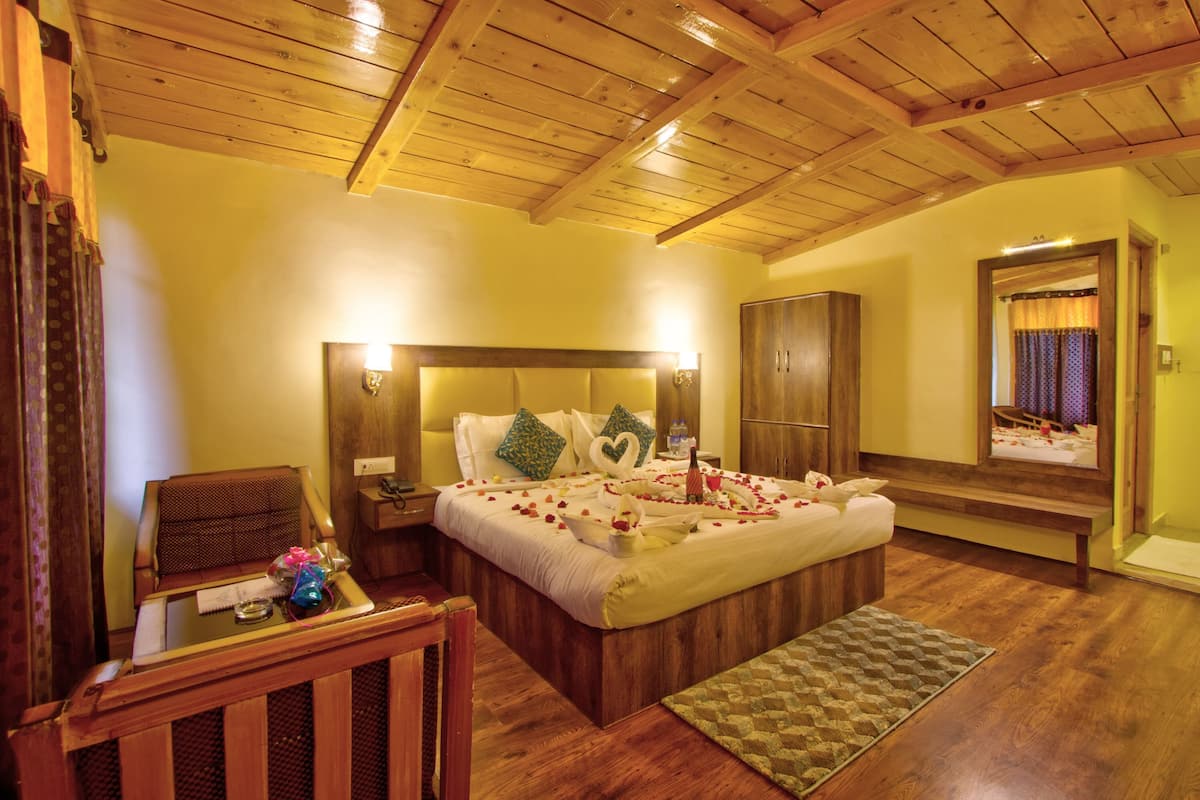 A bedroom with a wooden ceiling, a bed with a heart-shaped pillow, a bedside table, and a mirror.