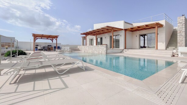 A rooftop pool area with lounge chairs, a pergola, and a stone wall. - Stylish Beach House 4 BR w/pool - 1 min from the beach! (Rhodes)