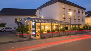 A hotel with a covered entrance, a staircase, and a car parked outside. - Apartment Dufour (Rheineck)