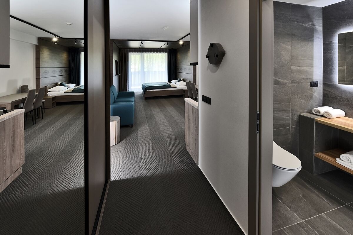 Une chambre d’hôtel moderne dotée d’un grand lit, d’un bureau, d’un canapé et d’une salle de bain séparée.