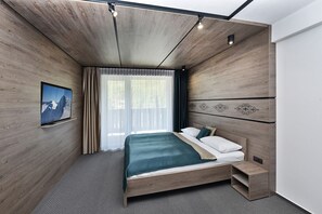 A modern bedroom with a wooden bed, a small bedside table, and a built-in bench. - Tri sestry  (Demanovska Dolina)