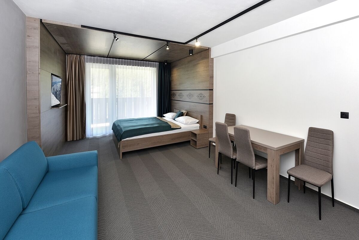 Ein modernes Hotelzimmer mit einem Bett, einem Schreibtisch und einem blauen Sofa.
