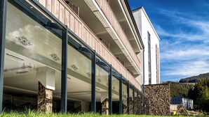 A modern building with a glass facade, stone pillars, and a wooden balcony.