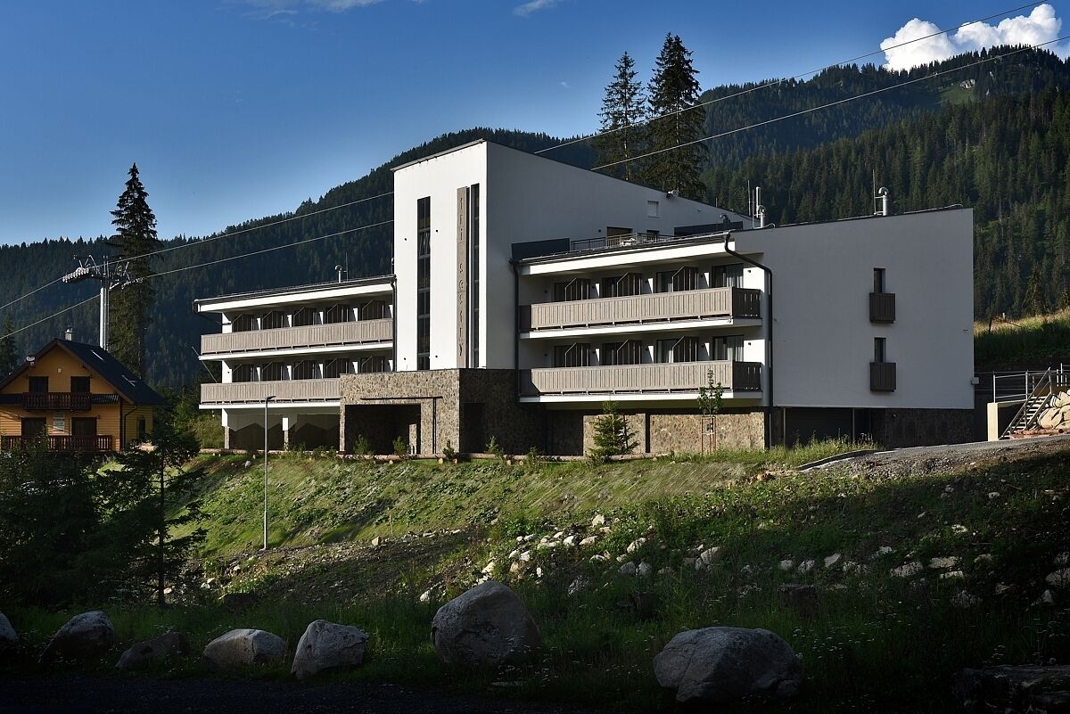 Een modern gebouw met een plat dak, twee balkons en een groot raam.
