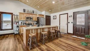 Una cocina amplia con armarios de madera, una isla grande con taburetes, un refrigerador y un microondas.