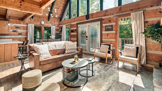 A cozy cabin interior with a wooden interior, a sofa, a coffee table, and a dining area.