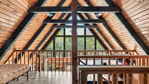 An attic bedroom with a wooden ceiling and a large window.