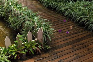 A wooden pathway with potted plants and a small water feature.
