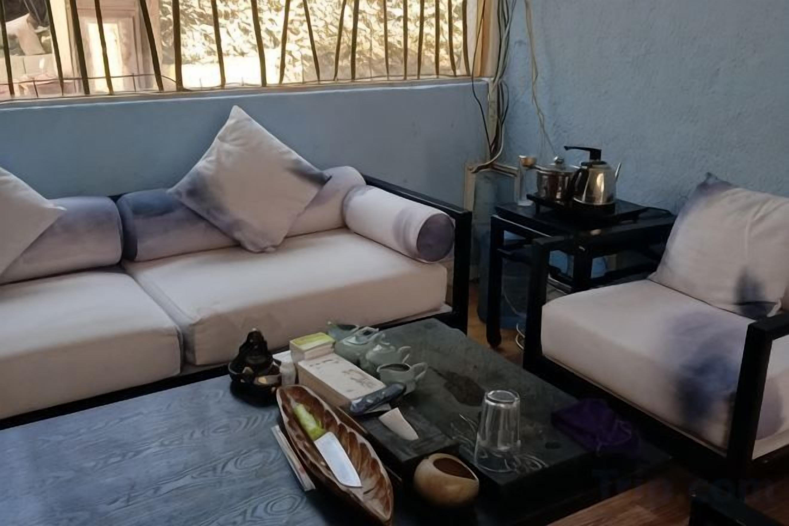 Una sala de estar con sofá, mesa de centro y una mesita auxiliar con utensilios de cocina.