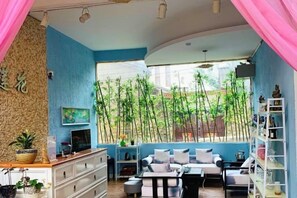 Una habitación con pared azul, un armario de madera, un sofá, un televisor y una estantería.