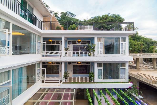 Un edificio de varios pisos con balcones, grandes ventanales y techo plano.