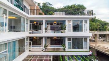 Un edificio de varios pisos con balcones, grandes ventanales y techo plano.
