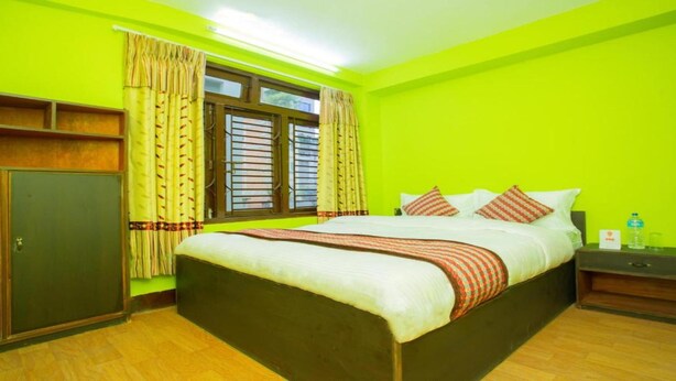 A room with a bed, a nightstand, a wardrobe, and a window with curtains.