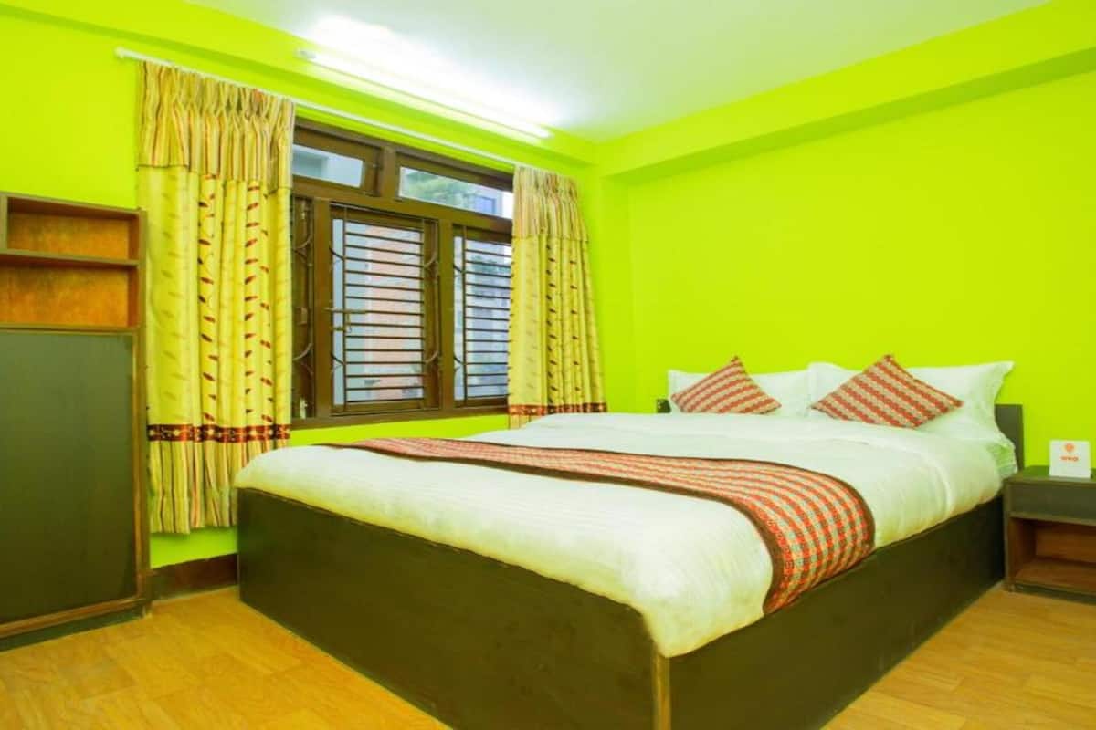 A room with a bed, a nightstand, a wardrobe, and a window with curtains.