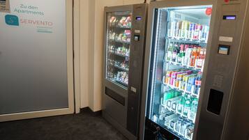 Two self-service beverage vending machines in a hallway.