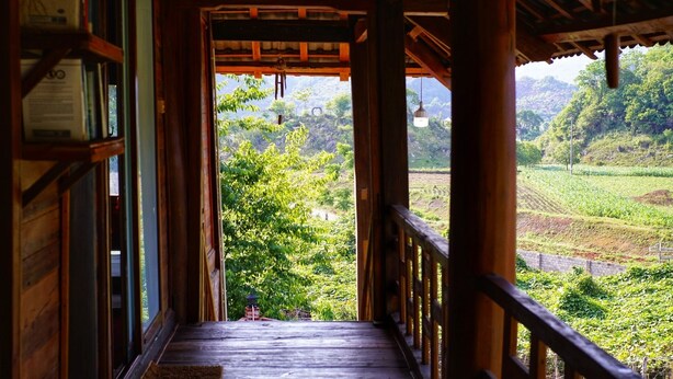 A wooden porch with a view of a lush green landscape. - Farmstay Ban Bua (Moc Son)