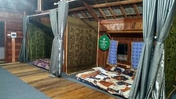 Una habitación con techo de madera, cama con ropa de cama estampada, cortinas y un letrero verde en la pared.