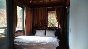 A bed with a wrought iron headboard in a room with a window and curtains. - Farmstay Ban Bua (Moc Son)