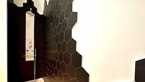 Un bagno moderno con una parete di fondo in piastrelle esagonali, un lavandino bianco e una zona doccia.