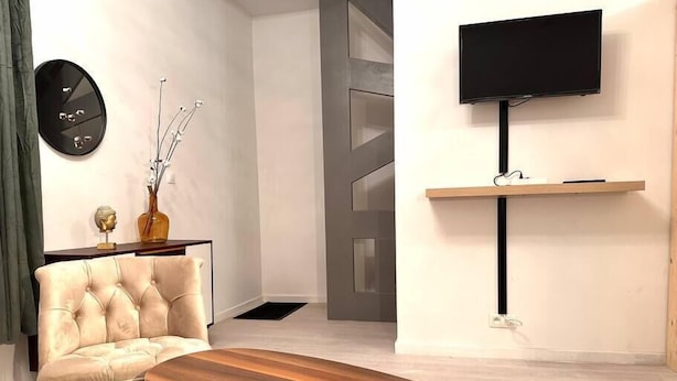 Un soggiorno moderno con un divano, un tavolino in legno, una TV a parete e un vaso decorativo.
