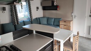 Une petite cuisine équipée avec une cuisinière à gaz, une petite table à manger et un banc intégré avec des coussins.