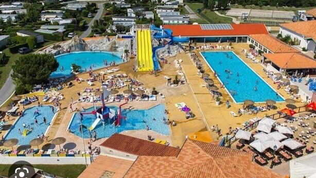 Vue aérienne d’un complexe hôtelier doté de plusieurs piscines, d’un toboggan aquatique et de chaises longues.