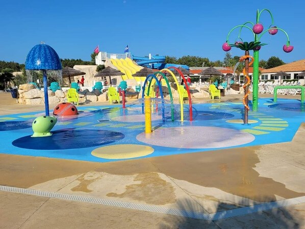 Un parc aquatique doté de structures de jeux colorées, d’un toboggan et d’un espace piscine.