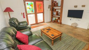 Una sala de estar con un sofá de cuero, una mesa de centro de madera, un televisor y una estantería.