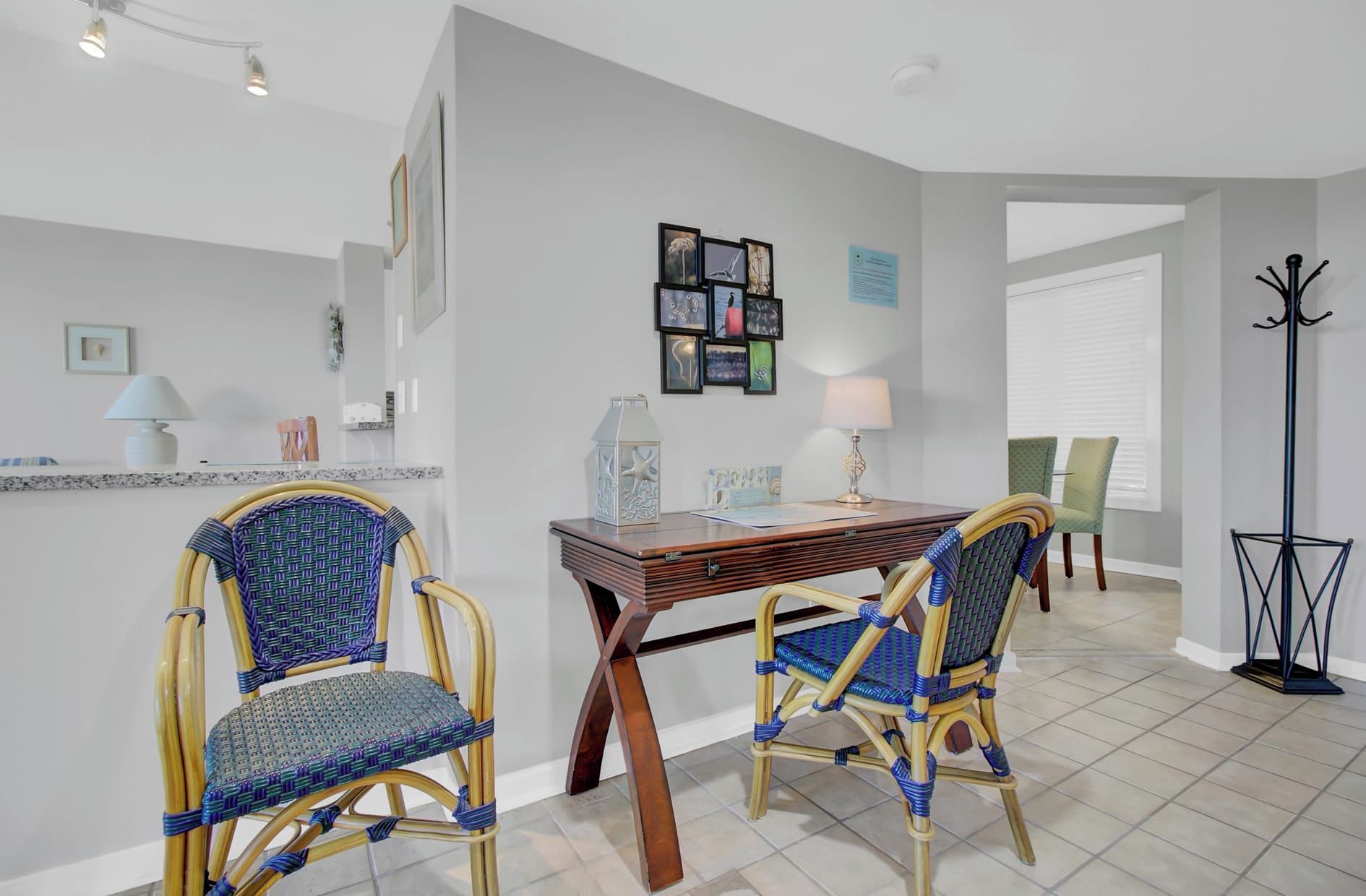 A dining area with two wicker chairs, a wooden table, and a floor lamp.