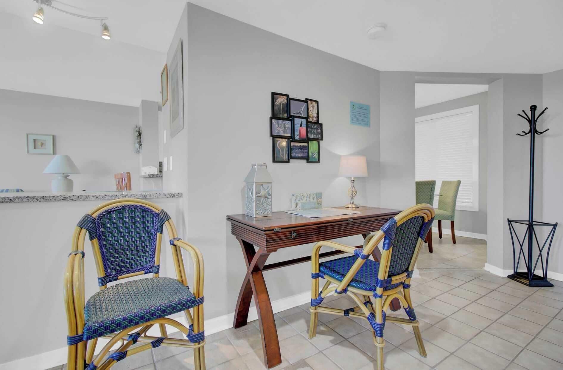 A dining area with two wicker chairs, a wooden table, and a floor lamp.