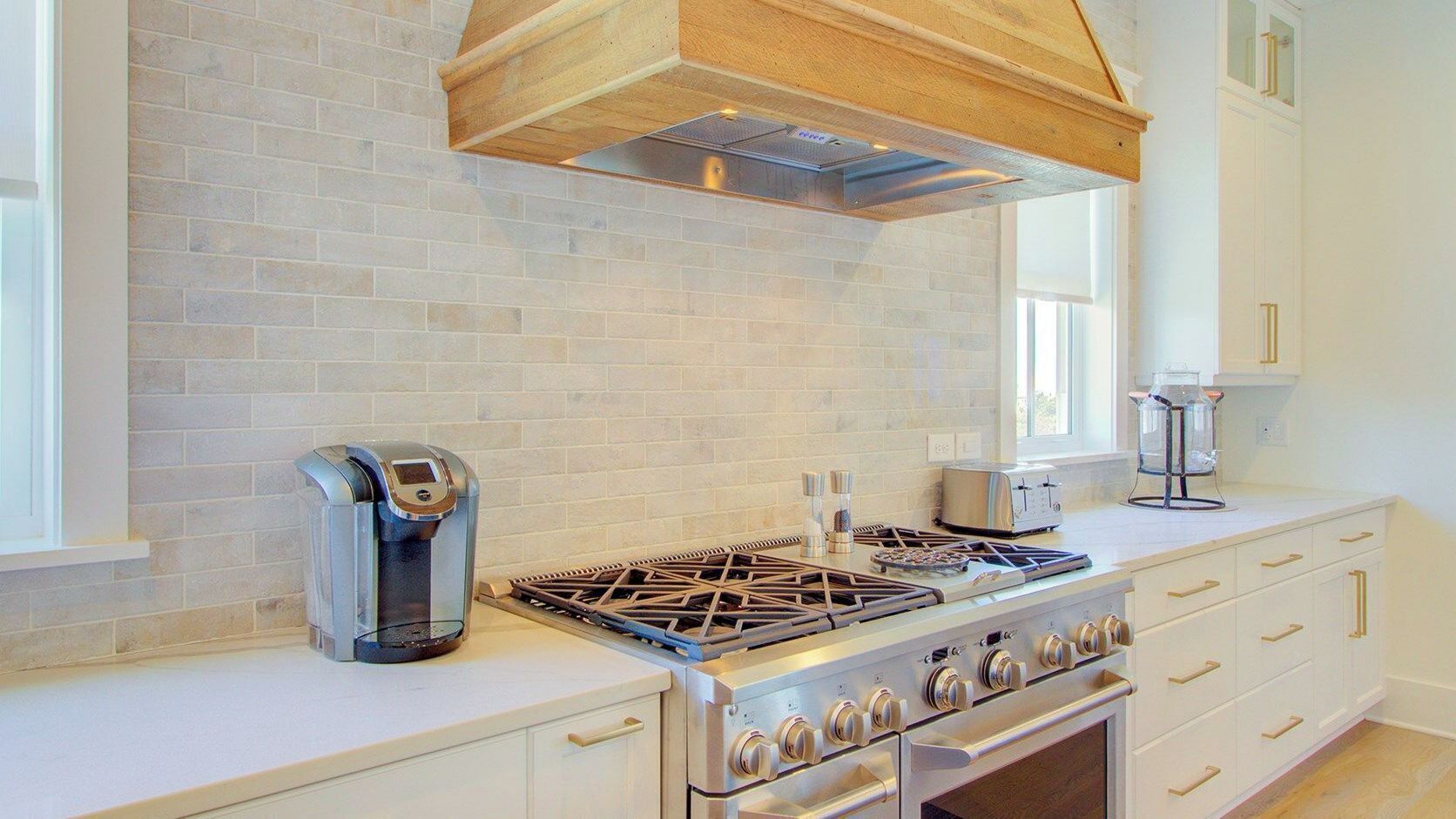 A kitchen with a gas stove, a coffee maker, and a window.