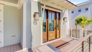 A house with a wooden front door, a porch, and a small balcony with a railing.