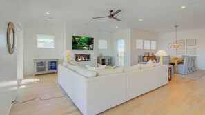 A modern living room with a large sofa, a fireplace, a television, and a dining area.