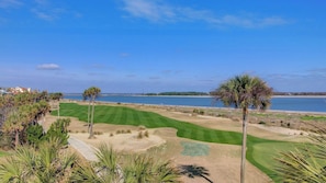 Campo de golfe com vista ampla para o oceano e costa distante.