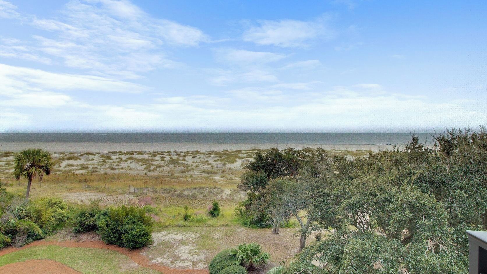 Un paysage côtier avec vue sur la mer, une végétation clairsemée et un ciel dégagé.